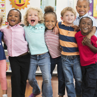 Portrait of smiling students hugging in classroom